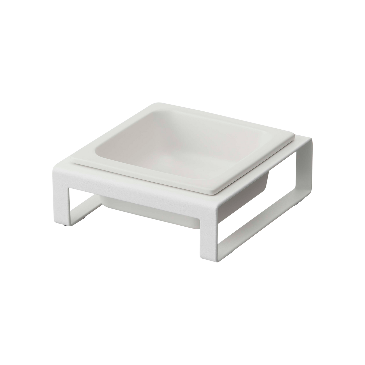 Introducing the Yamazaki Home Single Pet Food Bowl in white, a modern and minimalist accessory featuring a square bowl crafted from steel and ceramic. This sleek design comes with a matching elevated stand, complemented by non-scratch silicone protectors. Its clean, straight lines provide a contemporary touch, making it perfect for serving your pet's meals or enhancing your home's stylish decor.