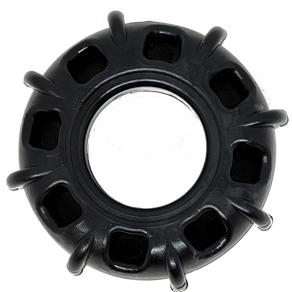 The SodaPup ID Tractor Tire EChew Ultra Durable Nylon Chew & Enrichment Toy is a black, circular tire-shaped dog toy with a hollow center and rectangular holes, shown from above on a white background.