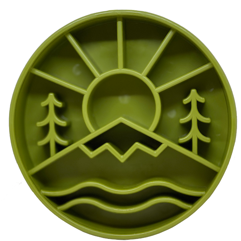 The Great Outdoors Design eBowl Enrichment Slow Feeder Bowl for Dogs by SodaPup, in a green round mold, showcases a scenic design with a sun, two trees, mountains, and wavy lines that resemble water.