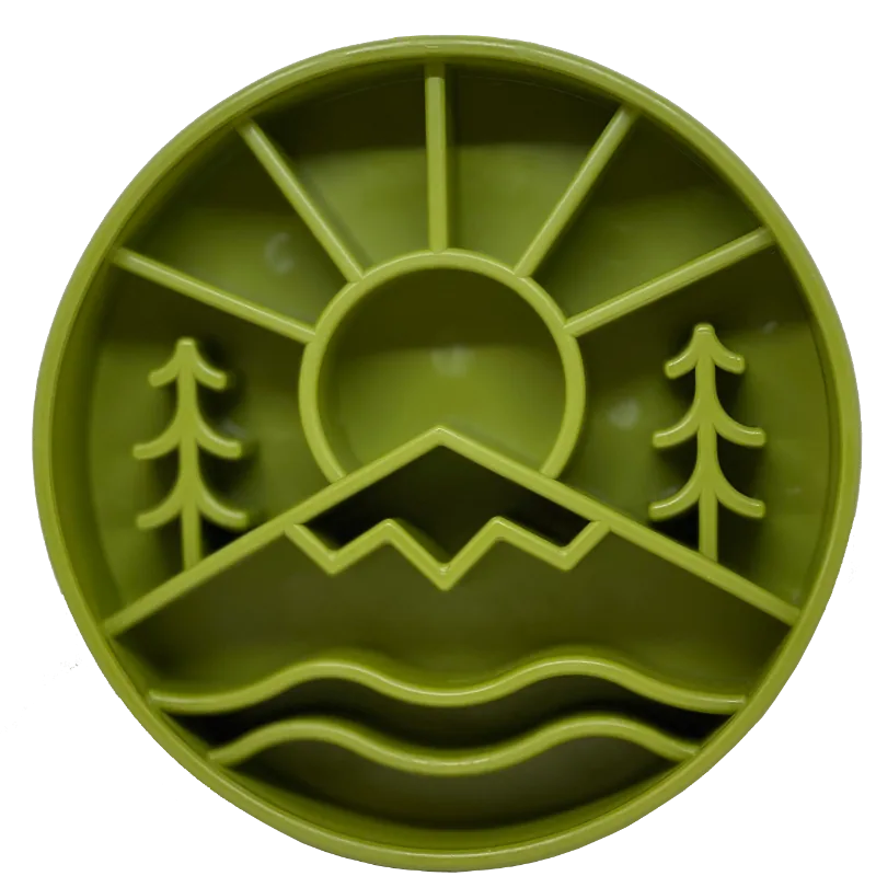 The SodaPup Great Outdoors Design EBowl is a round green plastic slow feeder dog bowl with sun, mountains, pine trees, and water motifs for a nature-inspired look that encourages slower eating.