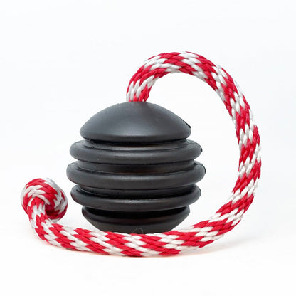 The SodaPup USA-K9 Magnum Black Stars and Stripes Ultra-Durable Rubber Chew Toy, a tough black dental dog toy with ridges, has a red-and-white braided rope and is shown on a white background.
