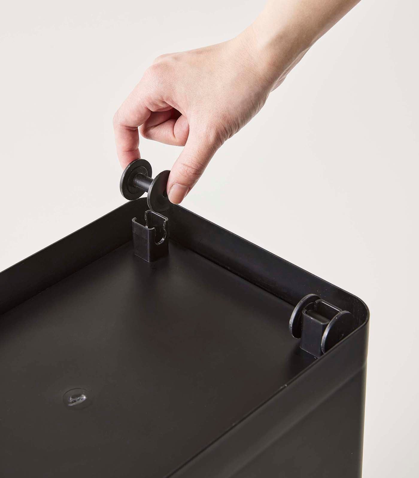 A person rolling open a Yamazaki Home Rolling Airtight Pet Food Container (25 Lbs.) with a handle and using a measured cup for kibble storage.