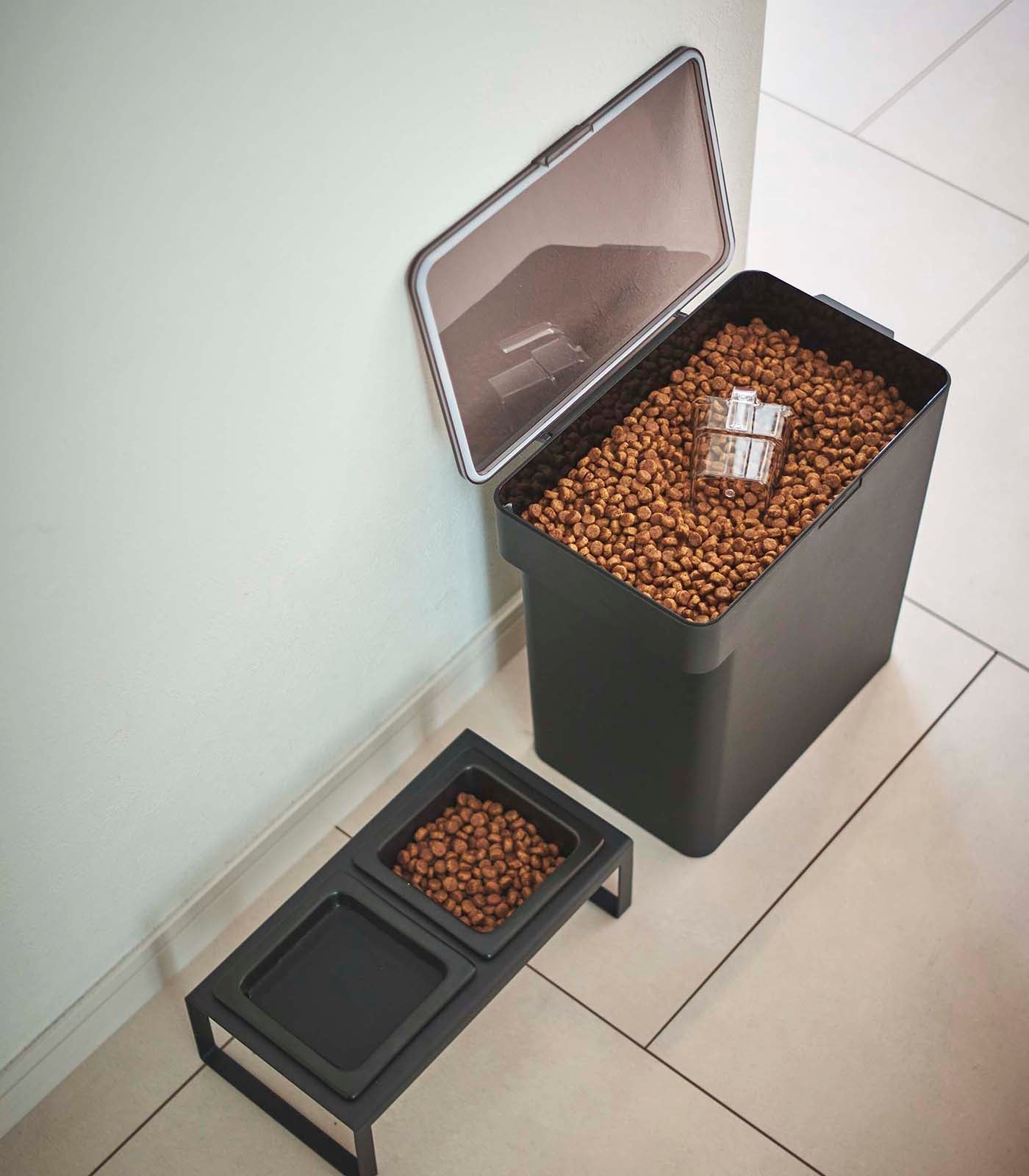 A Yamazaki Home Airtight Pet Food Container - Three Sizes with kibble next to a tiled floor.