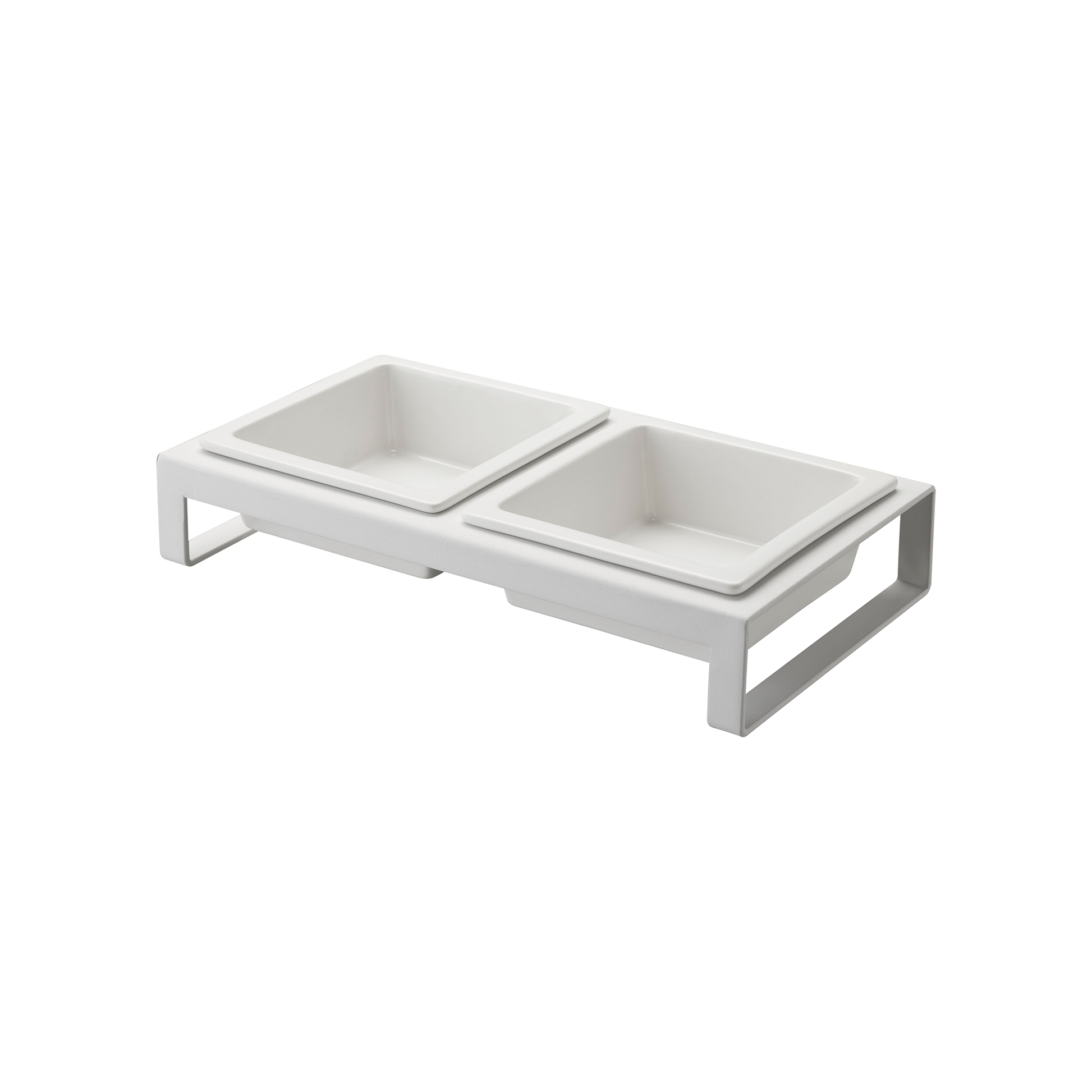 The Yamazaki Home Pet Food Bowl features a modern, white, elevated double feeder design with two square ceramic bowls resting on a sleek metal stand. This stylish setup is ideal for cats and small dogs, providing an elegant solution for their food and water requirements.