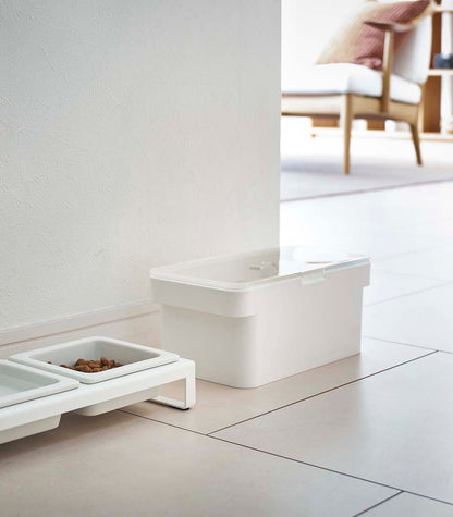 An Airtight Pet Food Container - Three Sizes by Yamazaki Home with a bowl of kibble next to it.