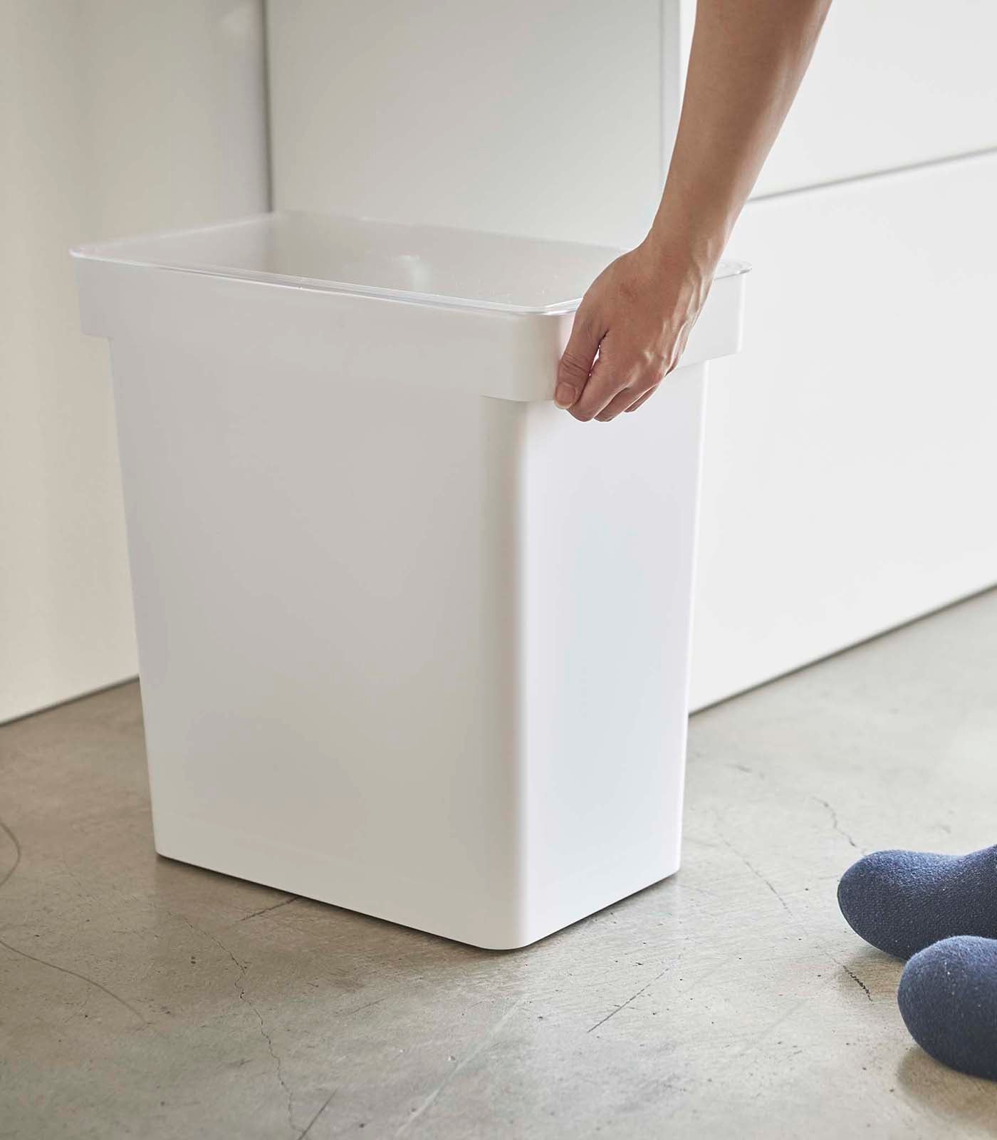 A person standing next to a Yamazaki Home Rolling Airtight Pet Food Container (25 Lbs.)