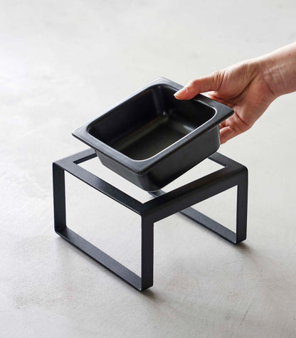 A person holding a Single Pet Food Bowl - Two Styles - Steel + Ceramic by Yamazaki Home.