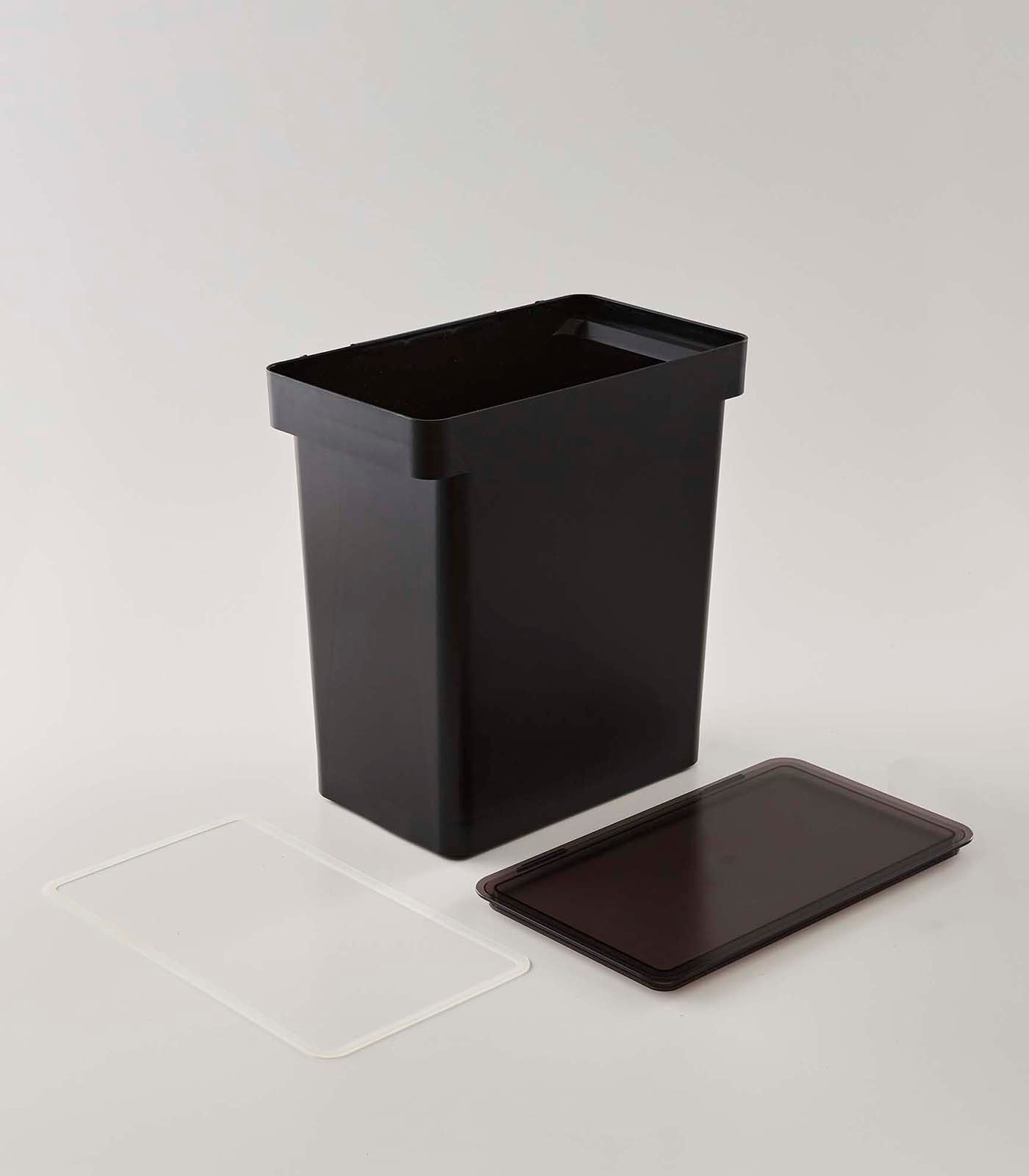 A black trash can next to a Yamazaki Home Rolling Airtight Pet Food Container (25 Lbs.) for an airtight kibble storage solution.