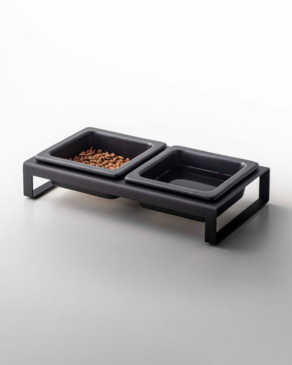 Modern pet feeding station with one Yamazaki Home ceramic Pet Food Bowl filled with kibble and one empty ceramic Pet Food Bowl, all set in a minimalist frame.