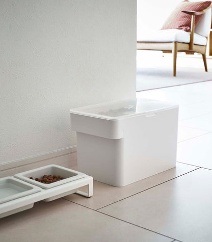 An Airtight Pet Food Container - Three Sizes from Yamazaki Home on the floor next to a scoop.