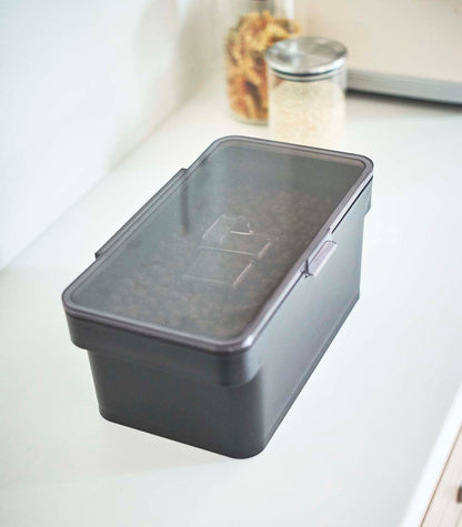 A Yamazaki Home Airtight Pet Food Container - Three Sizes, holding kibble, sitting on a counter.