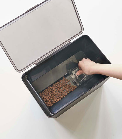 A person is scooping kibble into a Yamazaki Home Airtight Pet Food Container - Three Sizes.