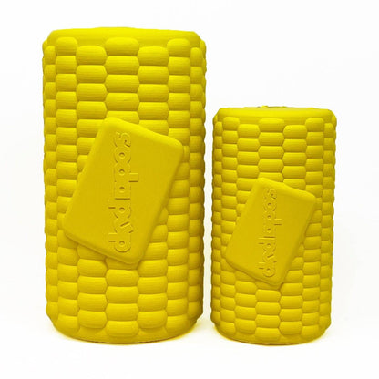 Two vibrant yellow containers, shaped like corn cobs, are positioned side by side on a white backdrop. Each features a rectangular label with embossed text. These Corn on the Cob EDispenser Durable Rubber Treat Dispensers by SodaPup have a textured, cylindrical design and are ideal for dispensing treats.