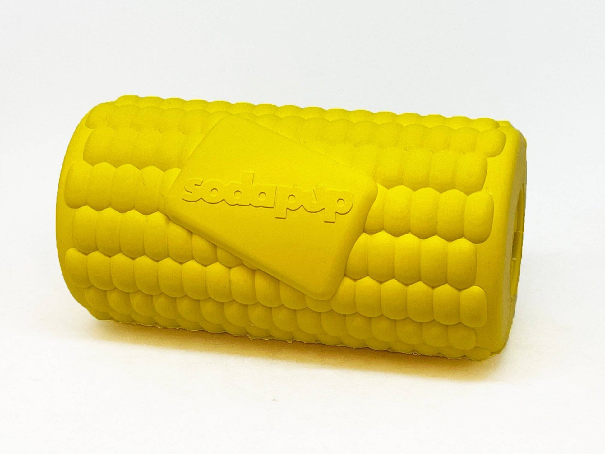 Introducing the Corn on the Cob EDispenser from SodaPup: a yellow, cylinder-shaped durable chew toy featuring corn kernel-like texture and the word "SodaPup" embossed on it, designed to dispense treats for endless fun.