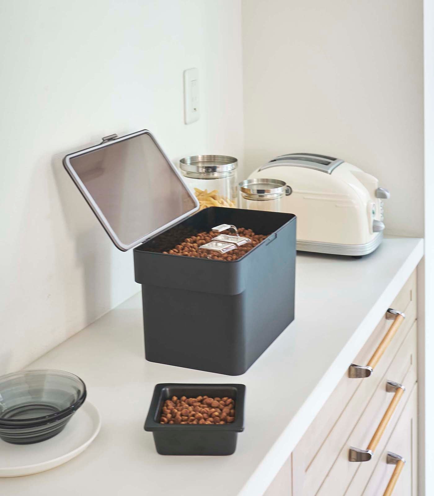 A kitchen counter with a box of cereal in a Yamazaki Home Airtight Pet Food Container - Three Sizes and a toaster.