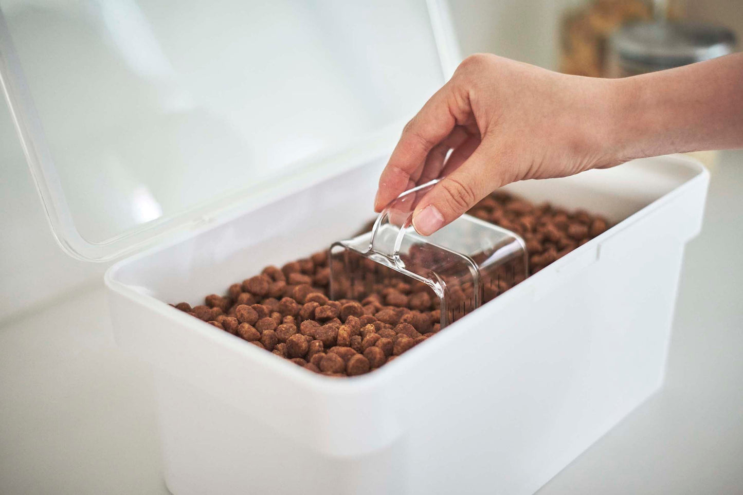 A person is scooping Yamazaki Home Airtight Pet Food into an airtight container.