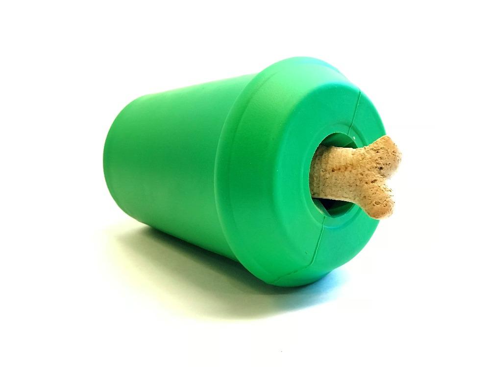 Featured here is the SodaPup Coffee Cup EDispenser, a durable rubber chew toy that also functions as a treat dispenser. Its unique design includes a cylindrical shape with an opening at one end, where a bone-shaped treat is partially inserted. This vibrant green toy rests on a light surface, poised to engage and entertain your furry friend.