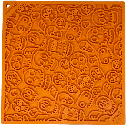 A large orange Zombie Design Emat Enrichment Lick Mat with skulls on it, perfect for dog enrichment and calming mat activities by SodaPup.