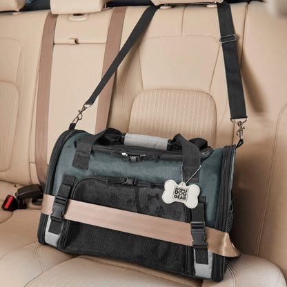 A black and grey messenger bag with multiple compartments rests on a tan car seat, secured with a seatbelt. A laptop is partially visible in one compartment, next to a Mobile Dog Gear Pet Carrier Plus designed for mobile dog gear.