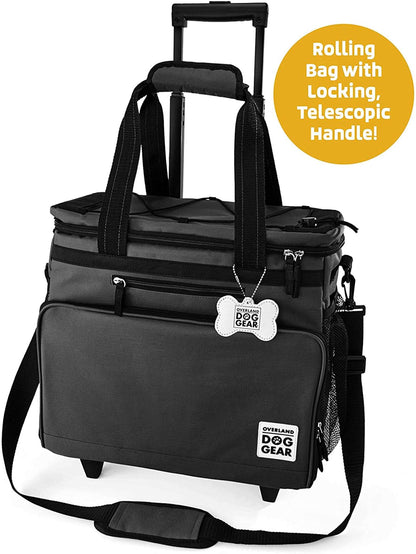 A black Mobile Dog Gear Rolling Week Away Dog Travel Bag designed for pet travel, featuring a telescopic handle, multiple compartments, and a brand label labeled "overland dog gear.