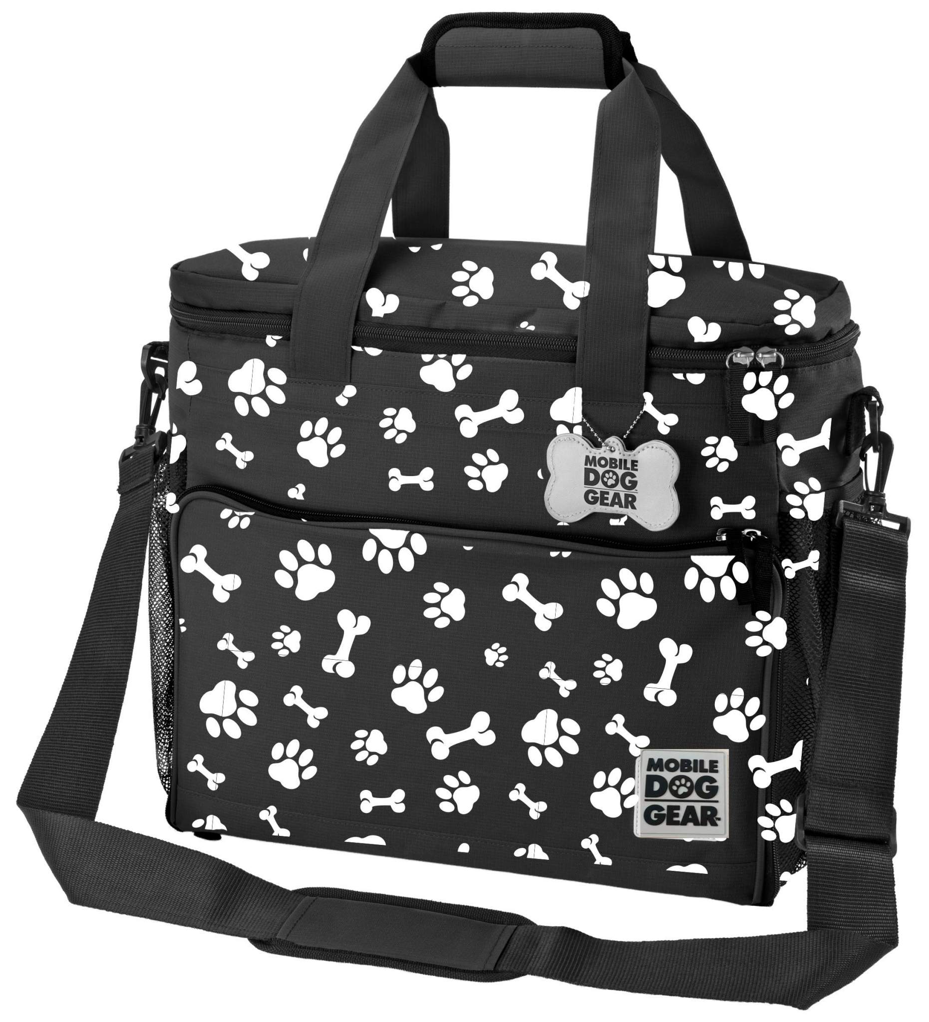 A black Mobile Dog Gear Large Week Away® Tote Bag decorated with white paw prints, featuring multiple compartments and a shoulder strap, labeled "mobile dog gear".