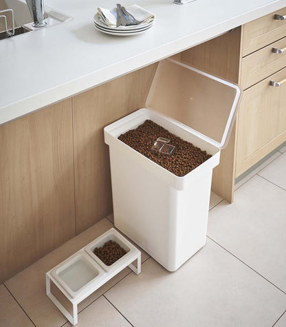 A Yamazaki Home Rolling Airtight Pet Food Container (25 Lbs.) on a kitchen counter designed for measured cup dispensing and easy rolling access.